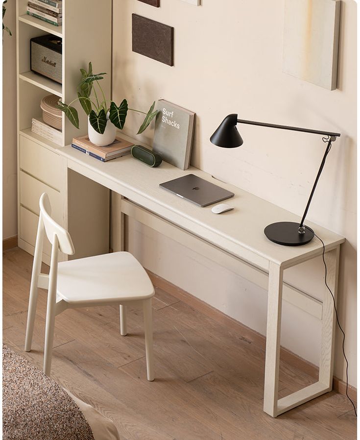 a white desk with a laptop, lamp and bookshelf in the corner next to it