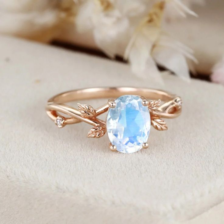 an oval blue topaz ring with leaves on the band and a center stone surrounded by diamonds