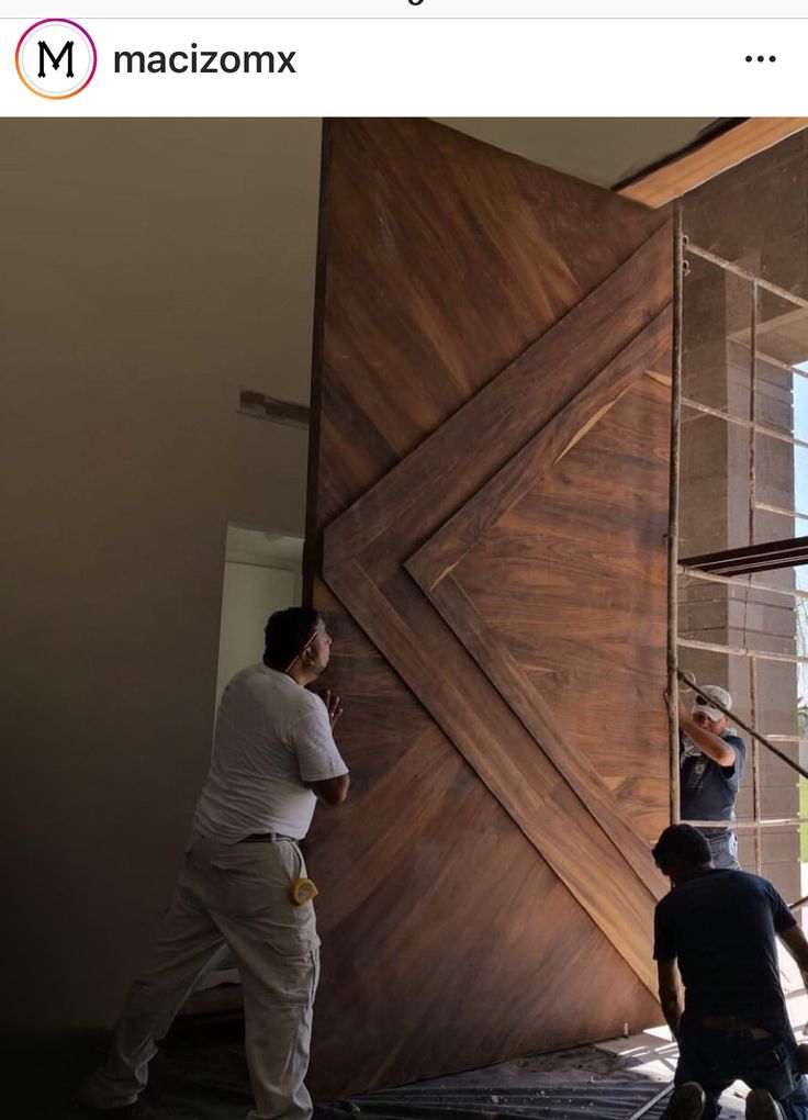 two men are working on a wooden wall