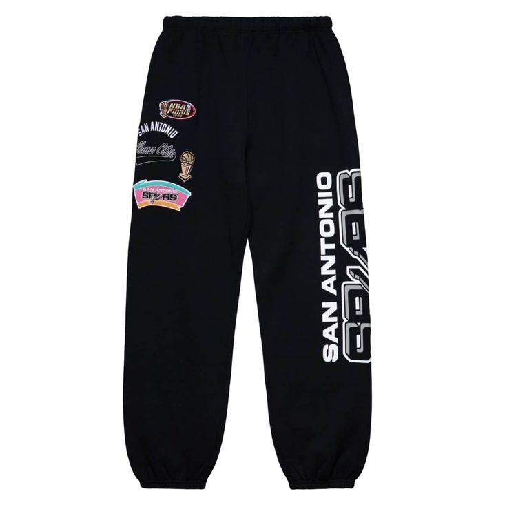 Show off your team spirit with these San Antonio champ city graphic joggers from your favorite vintage sports apparel brand, Mitchell & Ness. Both the silhouette and the patches call on vintage sports aesthetics, while the black background allows for effortless pairing. Whether you need an iconic pant for a lowkey night out or a stylish night in, these joggers will make their way to number one in your rotation. $49.95 Retro Streetwear Bottoms With Letter Print, Cotton Sweatpants With Letter Print For Streetwear, Retro Bottoms With Letter Print For Streetwear, Retro Letter Print Bottoms For Streetwear, Black Logo Print Joggers For Streetwear, Casual Sweatpants With Graphic Print For Streetwear, Casual Streetwear Joggers With Three Stripes, Urban Cotton Joggers With Letter Print, Retro Graphic Print Bottoms For Streetwear