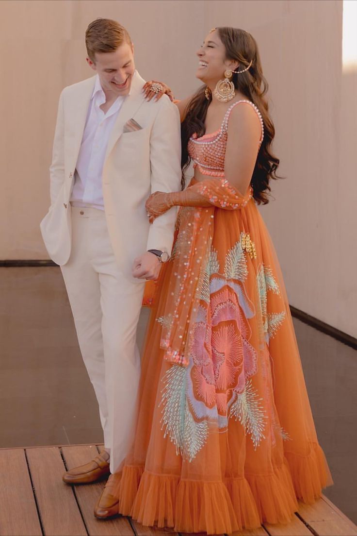 Modern outfit ideas for bride and groom for a minimal mehndi Orange Mehendi Outfit, Simple Mehendi Looks For Bride, Mendhi Night Outfits, Orange Haldi Outfit For Bride, Carnival Wedding Outfit, Mehendi Outfits For Guests, Haldi Carnival Outfit, Outfits For Mehendi Function, Maternity Lehenga