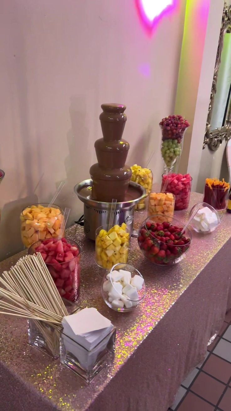 a table topped with lots of candy and candies next to a fountain filled with chocolate