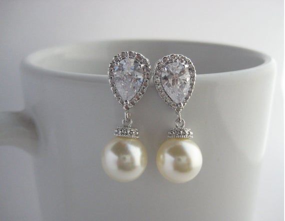 Classic cubic zirconia and pearl bridal earrings in rhodium plated brass setting. Earrings feature clear cubic zirconia teardrop ear post and a 10mm Swarovski cream pearl dangle drop. Total length of the earrings is 2.7 cms.For matching necklace click:https://www.etsy.com/listing/252977878/cream-pearl-and-crystal-bridal-necklace?ref=shop_home_active_10For matching bracelet click:https://www.etsy.com/listing/253699301/classic-bridal-cream-pearl-bracelet?ref=shop_home_active_5 To browse my collect Diamond White Cubic Zirconia Pearl Earrings For Wedding, Silver Pear-shaped Cubic Zirconia Bridal Earrings, Silver Pear-shaped Bridal Earrings For Anniversary, Wedding Cubic Zirconia Round Pearl Earrings, Round Cubic Zirconia Pearl Earrings For Wedding, White Gold Cubic Zirconia Pearl Earrings For Wedding, Wedding Round Cubic Zirconia Pearl Earrings, Pear-shaped Sterling Silver Pearl Earrings For Wedding, Silver Pearl Bridal Earrings For Mother Of The Bride