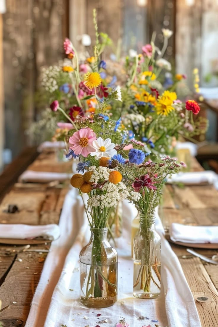 several vases filled with flowers sitting on top of a wooden table