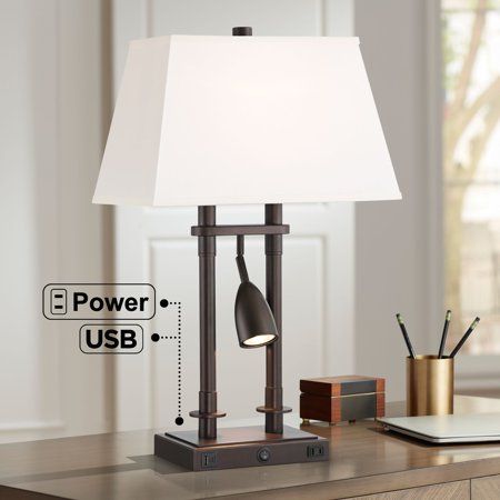 a desk lamp sitting on top of a wooden table next to a laptop and pen