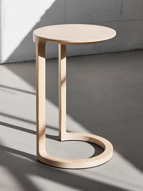 a wooden table sitting on top of a floor next to a white wall and window