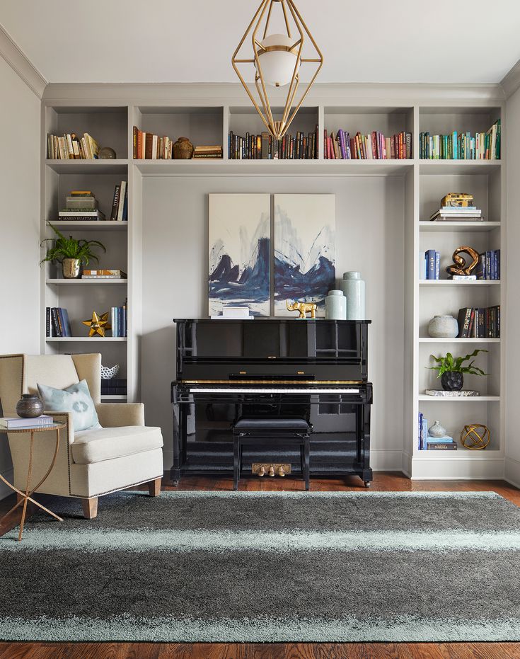 a living room filled with furniture and a piano in front of a book shelf full of books