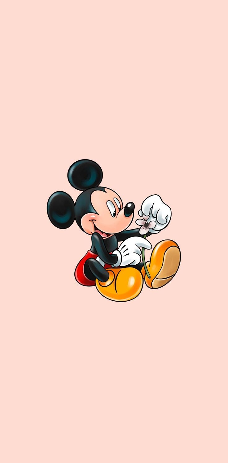 the mickey mouse is sitting on top of an orange and looking at it's face