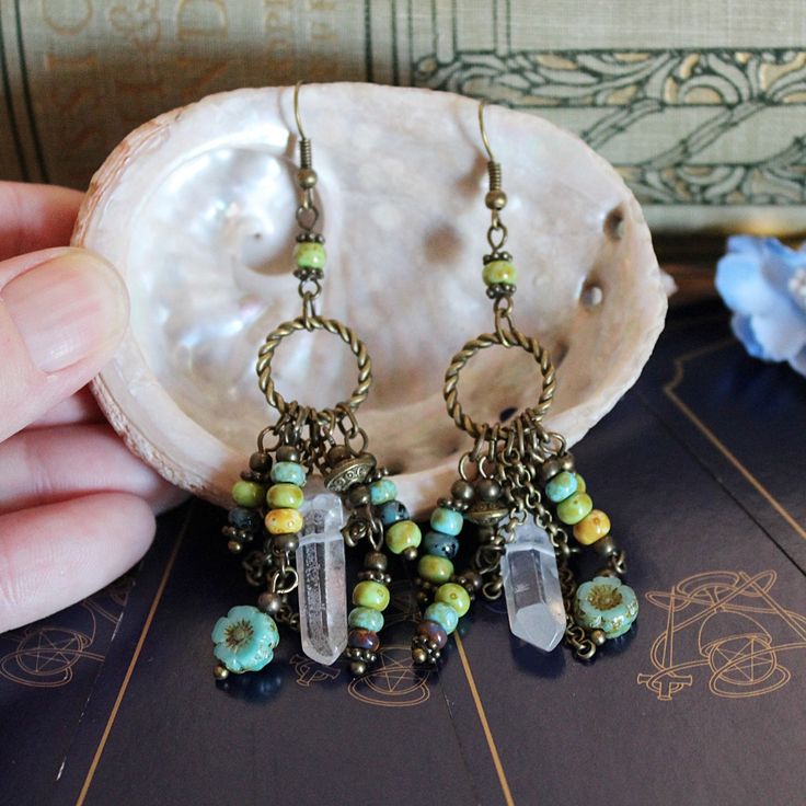 Australian made, Earth goddess bohemian earrings for your boho pagan jewelry collection! Handcrafted beaded chandelier earrings with a hippie witchy tribal vibe These long dangling ooak, handmade statement earrings were created with... Rustic Czech glass beads. Czech flower beads. Quartz crystal points. Bronze chain. Bronze circles. These long dangle drop earrings measure 8 cm long.  These bronze boho crystal earrings weigh 6 grams each. The perfect accessory to create that green witch style!  A Unique Chandelier, Witch Style, Beaded Chandelier Earrings, Earth Goddess, Goddess Jewelry, Boho Crystal, Witch Fashion, Pagan Jewelry, Beaded Chandelier