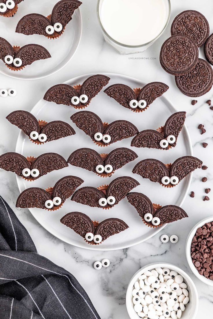 chocolate cookies decorated with eyes and googly eyes are on a plate next to bowls of cereal