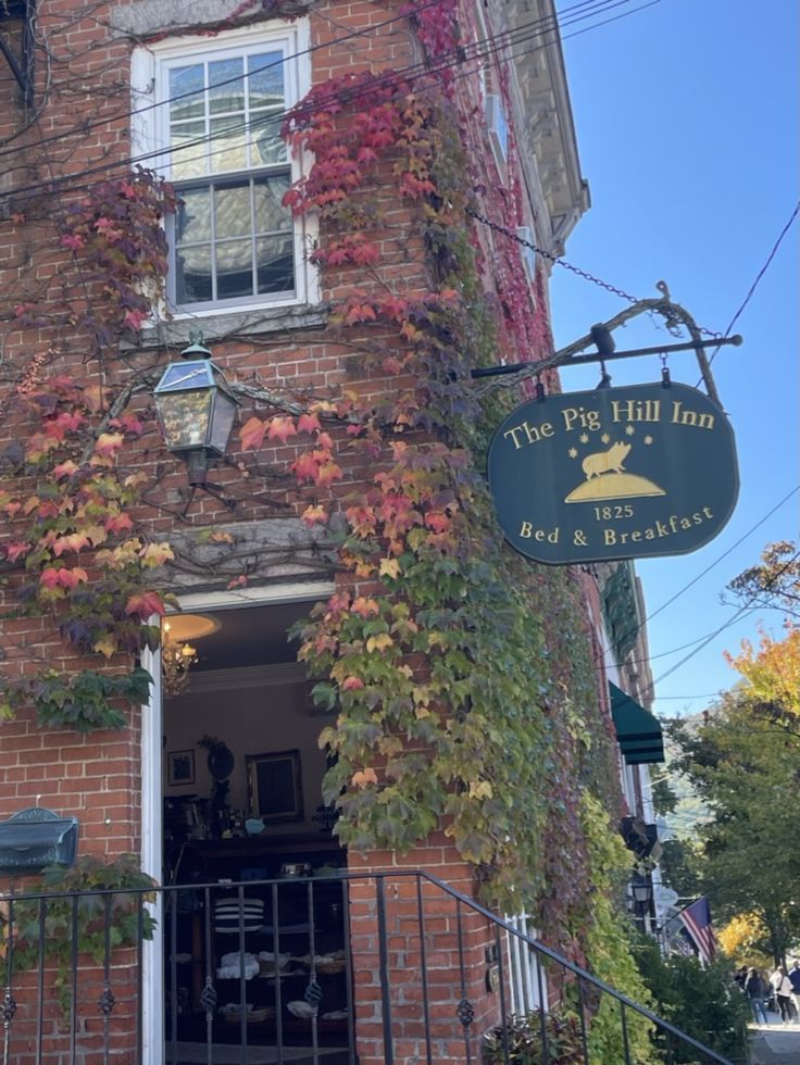 an old brick building with ivy growing on it's side and a sign that says the pig hill inn