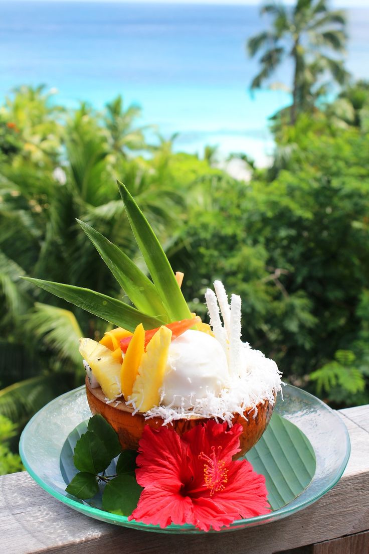 a plate with some fruit on it sitting on a wooden table next to the ocean