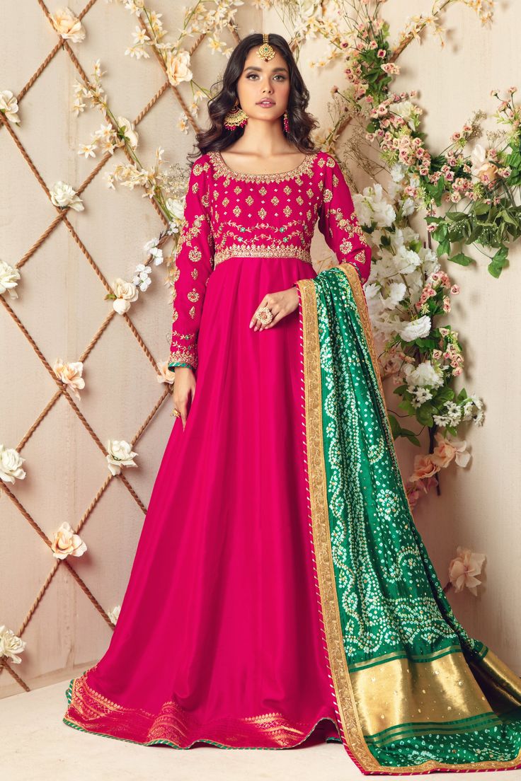 Over a canvas of Berry pink Raw-Silk, this swoon-worthy multi panel gown is crafted using delicate age-old zardozi techniques incorporating dabka, crystals, beads, stones, sequins and contrasting resham work and a hand-crafted tassel at back. Green Pure Silk Chunri dupatta with stunning kamdani details all over finished with gota border completes the look of this outfit making it a perfect choice for any festive occasion. Gown Fabric: Pure Raw Silk Gown Length: 60” (customisable, mention in orde