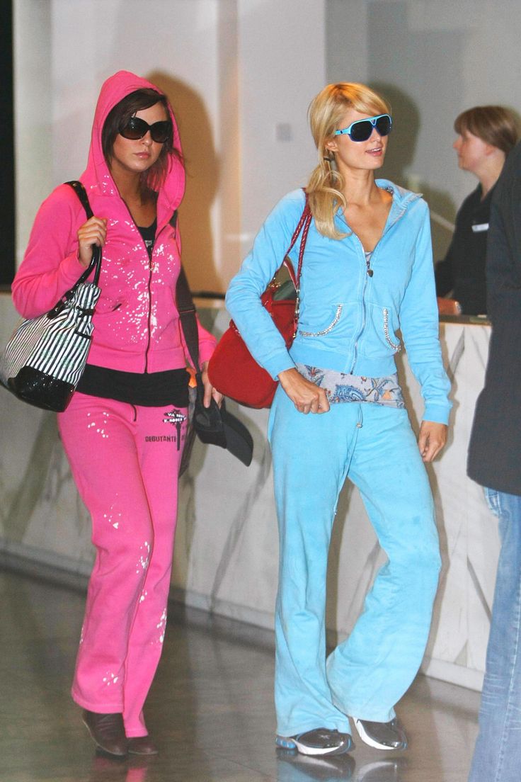 two women dressed in pink and blue walking through an airport