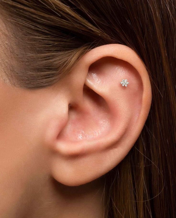 a woman's ear is shown with two small diamond studs on the side