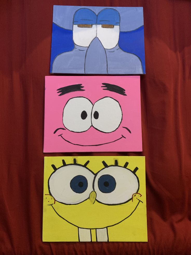 three paintings of cartoon characters on a red cloth covered tablecloth, one with blue eyes and the other with pink cheeks