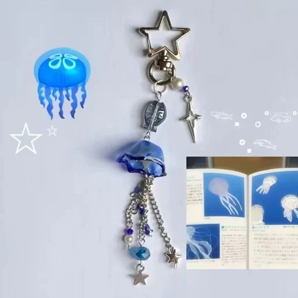 an open book with jellyfish and stars hanging from it's sides next to a key chain