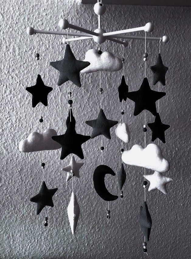 a black and white photo of a mobile with stars, moon and clouds hanging from the ceiling