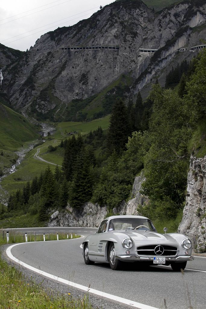 an old mercedes sits on the side of a mountain road