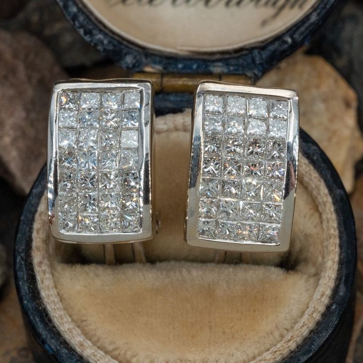 This pair of diamond earrings are each accented with twenty-eight (28), invisible set, princess cut diamonds. The earrings measure 13.1mm X 8.2mm and are finished with omega style backs. Luxury Rectangular Diamond Earrings With Accents, Princess Cut Diamond White Diamond Earrings For Anniversary, Rectangular Diamond Earrings With Accents For Formal Events, Wedding Earrings With Princess Cut Diamond Accents, Formal Square Cut Channel Set Jewelry, Luxury Single Cut Diamond Earrings For Anniversary, Formal Fine Jewelry Diamond Earrings Channel Set, Silver Princess Cut Diamond Earrings For Formal Occasions, Formal Rectangular Diamond Earrings With Accents