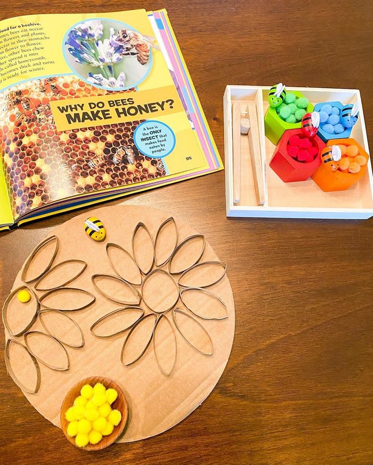 an open book and some crafting supplies on top of a wooden table with scissors