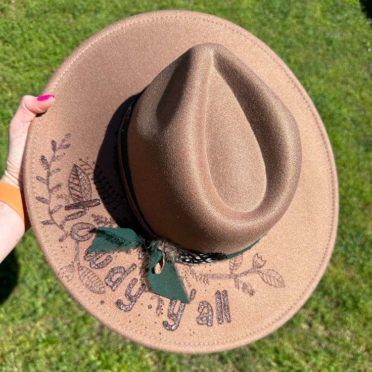 Turn heads wherever you go with this fun and stylish hat! What a fun piece to add to your wardrobe! This light brown hat features the saying  "howdy y'all"  with a floral surrounding. The saying and floral designs are hand burned. Premium Quality Branded Wide Brim Hats Each hat is hand burned. The hat pictured is the hat you will receive.  Vegan felt fedora hat Wide, stiff, flat brim. Stylish hat, wedding, everyday hat Structured wide brim panama hat in vegan felt. Flat and stiff brim Adjustable inner drawstring Crown size: 57 cm Brim: 4 in. 65% polyester 35% Cotton : This combination offers durability, comfort, and easy maintenance. Due to various sanitary concerns, hats are not returnable or exchangeable. Trendy Hats For Kentucky Derby Festival, Brimmed Felt Hat For Outdoor Spring Activities, Spring Brimmed Felt Hat For Outdoor, Spring Outdoor Brimmed Felt Hat, Spring Outdoor Felt Hat With Curved Brim, Spring Outdoor Wide Brim Felt Hat, Trendy One Size Fall Hat, Brimmed Sun Hat For Fall, Trendy Hats For Outdoor Fall Season