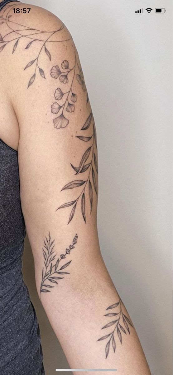 a woman's arm with tattoos on it and an olive branch in the middle