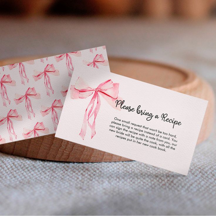 a close up of two business cards on a wooden plate with a ribbon tied around it