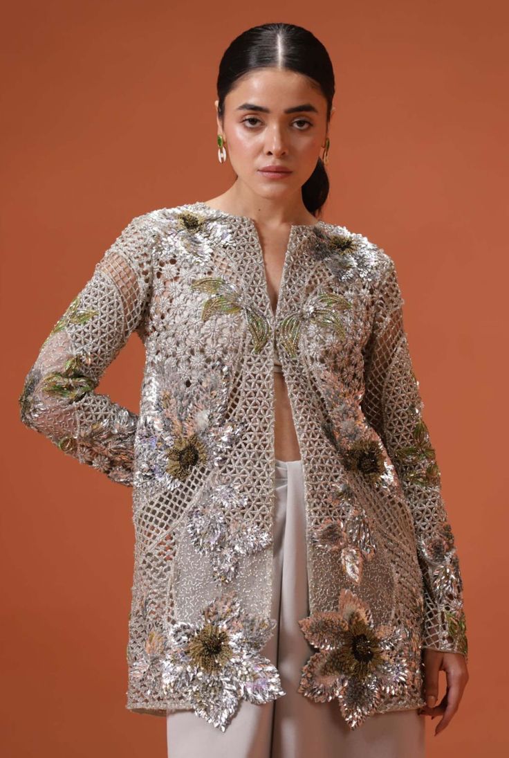 Introducing this silver soiree jacket, a heartfelt tribute to the time-honored techniques and materials of south asian craftsmanship. Combining traditional elements like dabka and naqshi with the contemporary dazzle of sequins and crystals, this masterpiece reinvents regional artistry for the modern world. Paired elegantly with a silver silk bustier and pre-draped pants, paying homage to the classic dhoti silhouette, this ensemble harmoniously blends the old and the new, celebrating the rich her Luxury Sequined Traditional Wear For Formal Occasions, Luxury Lace Traditional Designer Wear, Luxury Sequined Traditional Wear For Festive Occasions, Luxury Party Wear Sets With Zari Work, Luxury Long Sleeve Traditional Wear With Sequins, Luxury Formal Sets With Zari Weaving, Luxury Sequined Traditional Wear For Festivals, Luxury Party Wear Chinon Traditional Dress, Luxury Embellished Traditional Wear For Ceremonial Occasions