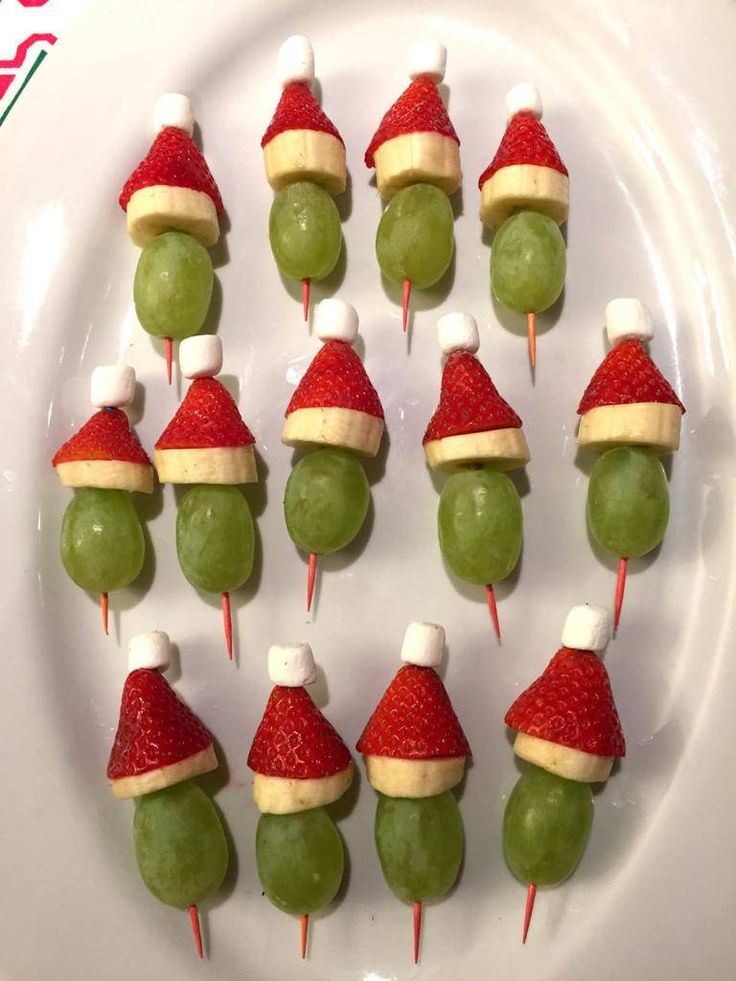 a white plate topped with fruit and veggies covered in santa's hats