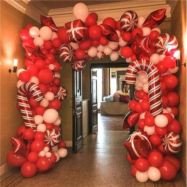 an arch made out of balloons and candy canes is decorated with red, white and silver decorations