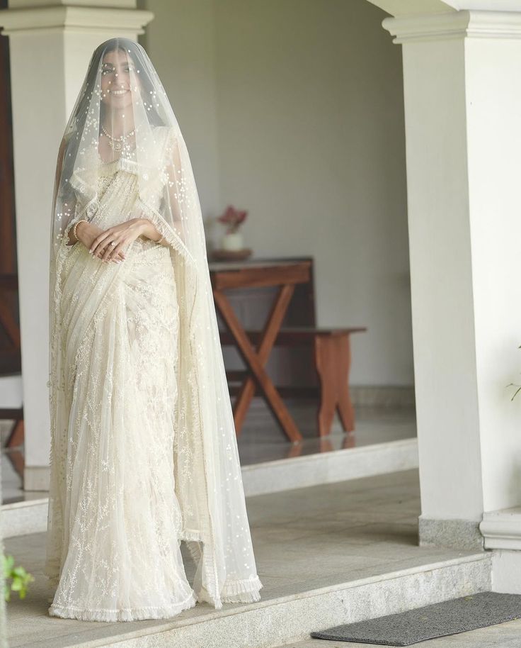 a woman in a white wedding dress and veil standing on steps with her hands behind her head