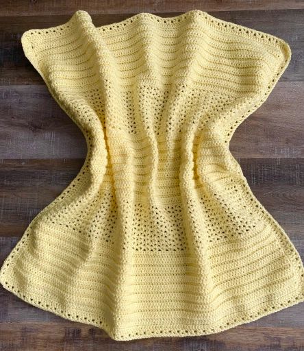 a yellow crocheted blanket sitting on top of a wooden floor