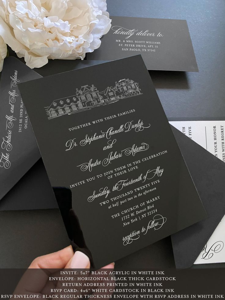 the wedding stationery is black and white with silver lettering on it, along with a bouquet of flowers