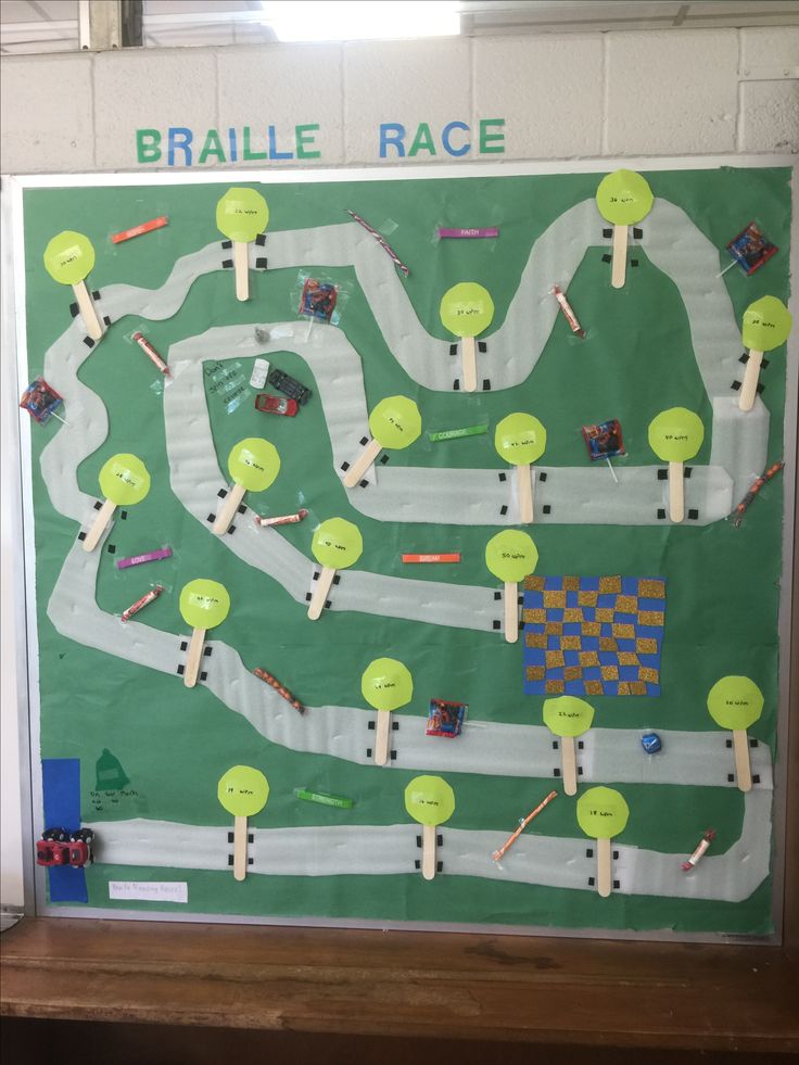 a bulletin board is decorated with legos and race track pieces on the wall in front of it