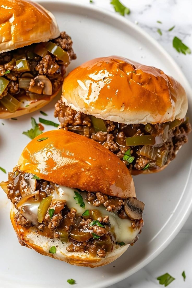 three sloppy joe sliders on a white plate with green onions and mushrooms in the middle