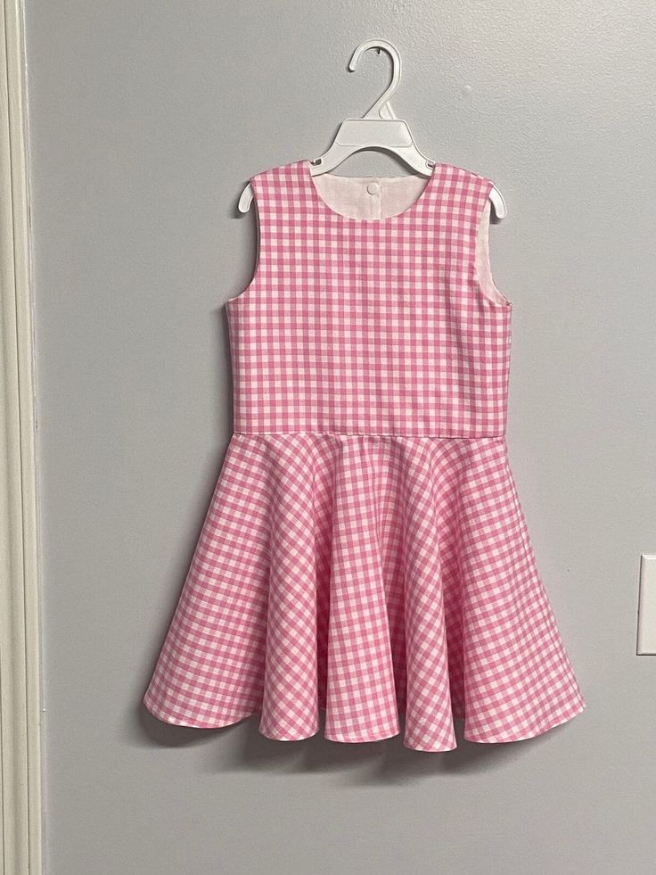 a pink and white checkered dress hanging on a wall