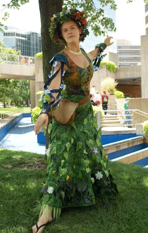 a woman dressed up like a hula dancer posing for the camera in front of a tree