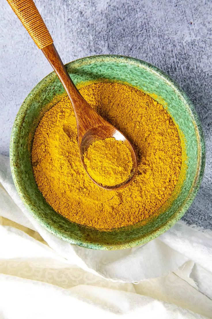 a bowl filled with yellow powder and a wooden spoon