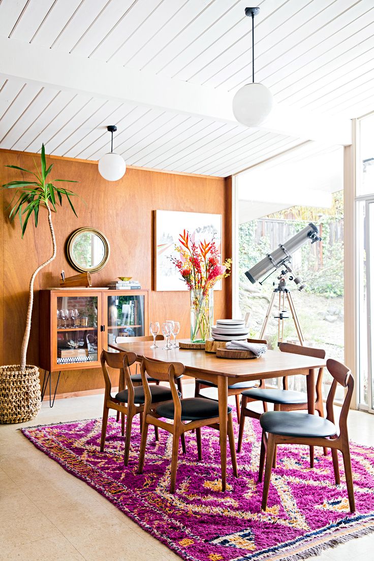 a dining room table with chairs and a rug in front of the window that overlooks an outdoor deck