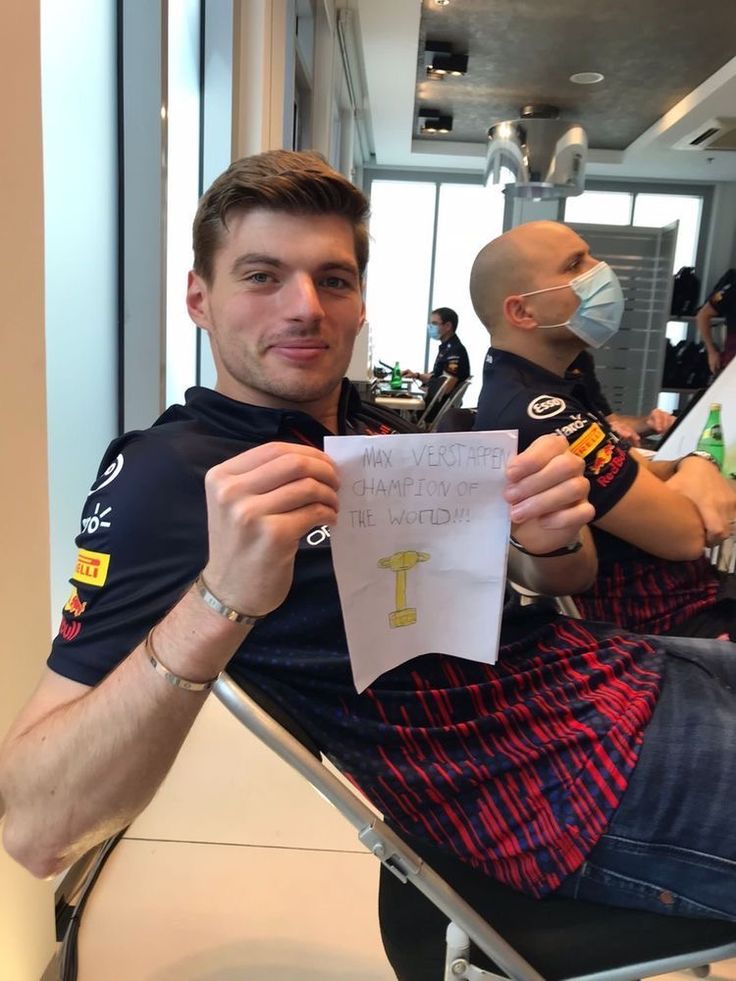 a man sitting in a chair holding up a piece of paper with a cross on it