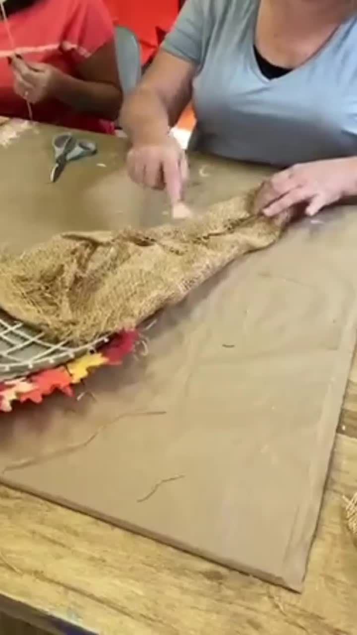 a woman is making something out of burlap on a table with other people