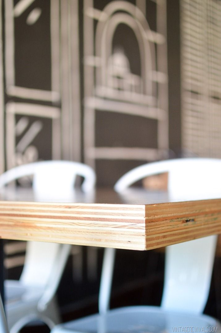 an empty table with white chairs in front of a black and white wall behind it