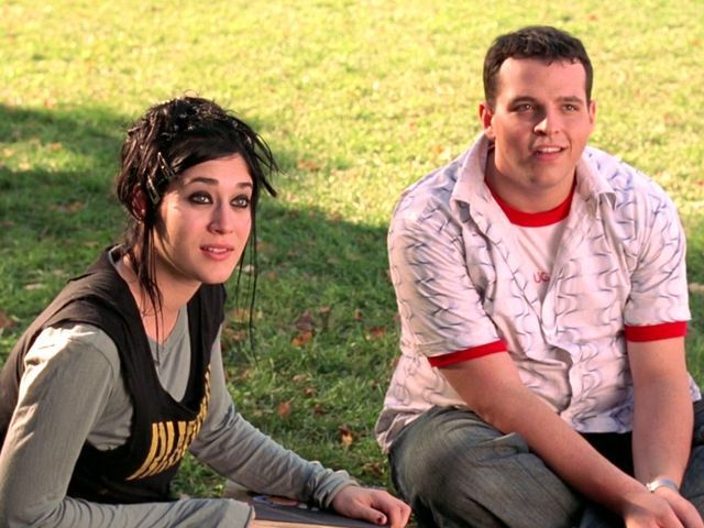 a man and woman sitting on the ground with their skateboards in front of them