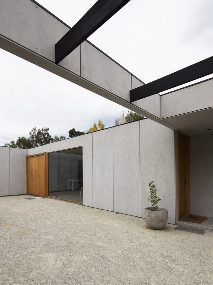 an empty courtyard with concrete walls and planter in the foreground, surrounded by wooden slats