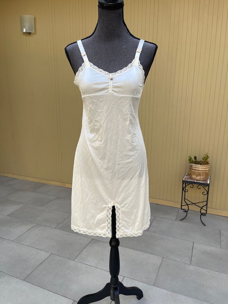 Her Majesty full slip dress Labeled a women's size 14 - Fits a modern size Small Measures (laying flat): 16" pit to pit and 34" long Adjustable straps Creamy white ivory color Lace trim, gathered at the middle of bust with cute little pink and green flower detail Excellent condition 100% Nylon See pictures for additional details White Slip Dress With Built-in Bra, White Fitted Camisole For Daywear, Fitted White Camisole For Daywear, Beige Slip Dress With Lace Trim For Daywear, Beige Fitted Camisole, White Lace Trim Slip Dress For Loungewear, White Day Dress With Adjustable Straps, White Daywear Dress With Adjustable Straps, Sleeveless Fitted Slip Dress For Daywear