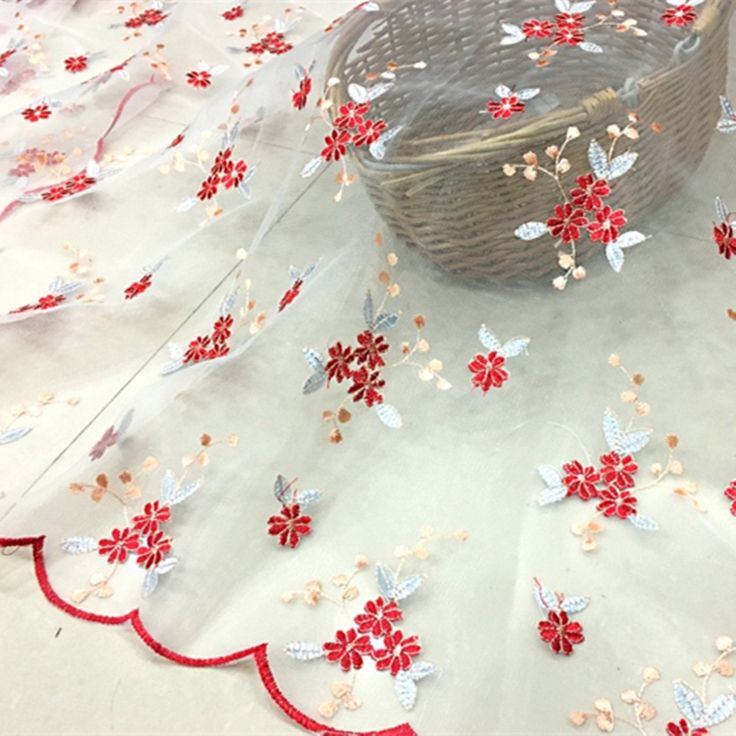 a basket sitting on top of a table covered in red and white fabric with flowers