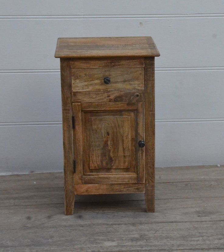 a small wooden cabinet sitting on top of a hard wood floor next to a white wall