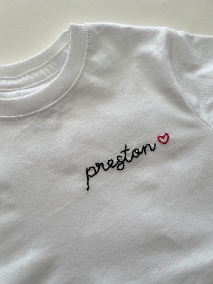 Simple and perfect.  Have your child's name on a classic white tee followed with a little heart. This no fuss name tee is great for Valentine's day or for any little heart obsessed child. Shirts are 100% cotton - slight shrinkage will occur after washing and dryer.  Please size up if between sizes. Returns and Exchanges: I do not accept returns on personalized pieces but will be happy to discuss any issues via messages. Thanks for visiting Sweet Olive Street and be sure to follow along on Instagram @SweetOliveStreet :) Family Matching White T-shirt With Embroidered Text, White Family Matching T-shirt With Embroidered Text, White Embroidered T-shirt For Family Matching, Custom Name White Crew Neck T-shirt, White Crew Neck T-shirt With Custom Name, White Short Sleeve Tops With Custom Name, Cute Personalized White T-shirt, Cute White T-shirt With Custom Name, Custom Name Cotton Top As A Gift