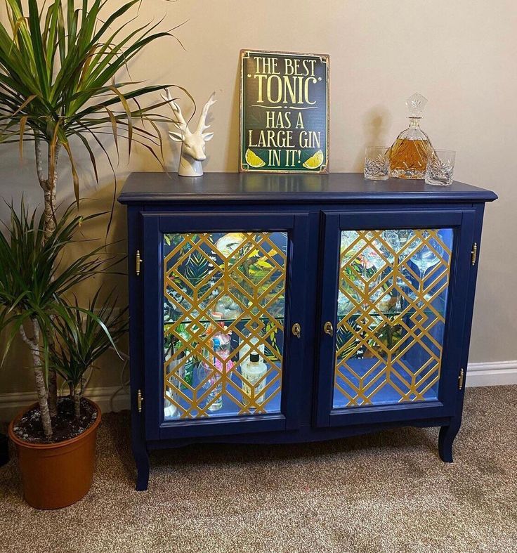 a blue cabinet with mirrored glass doors next to a potted plant